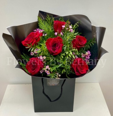 Bouquet featuring 6 luxury red roses with a filler florals, accented with diamanté in the roses, complemented by foliage, wrapped in luxury cellophane and matching gift bag, hand-tied in water.