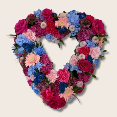 Open heart funeral tribute in pink and blue sapphire tones with luxury flowers and seasonal accents.