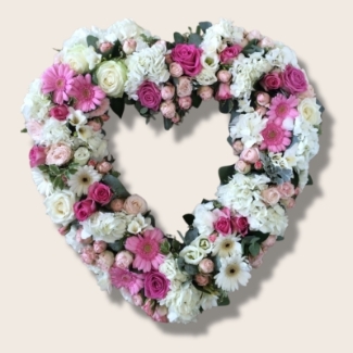 Modern open heart funeral tribute in pale pink and white with luxury flowers and soft foliage accents.