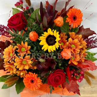 Pumpkin Spice bouquet with sunflower, orange gerbera, red roses, chrysanthemums and autumn foliage in gift wrap.
